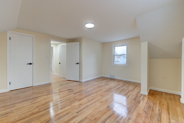 additional living space with vaulted ceiling and light hardwood / wood-style flooring