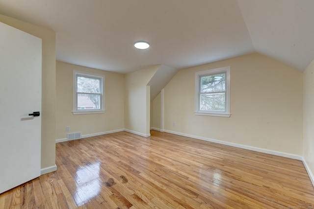 bonus room with lofted ceiling, a healthy amount of sunlight, and light wood-type flooring