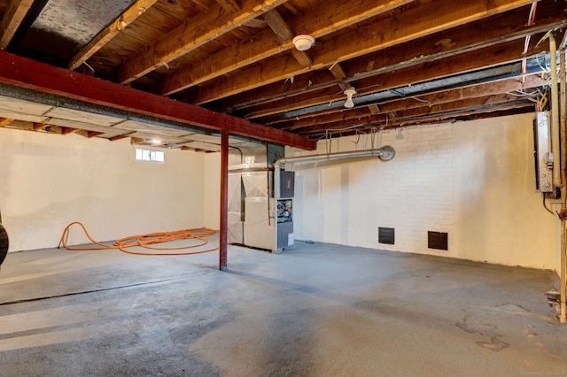 basement featuring brick wall, heating unit, and water heater