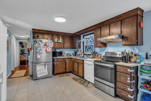 kitchen with dark brown cabinetry, sink, stainless steel appliances, and a textured ceiling