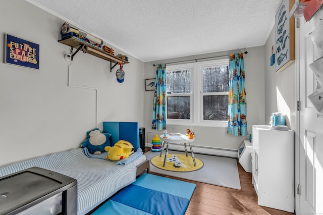 bedroom with hardwood / wood-style floors, a textured ceiling, and a baseboard heating unit