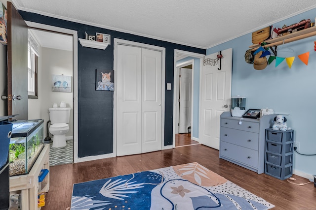 bedroom with ensuite bath, dark hardwood / wood-style floors, a textured ceiling, a closet, and ornamental molding