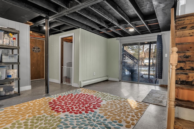 basement featuring baseboard heating and wooden walls