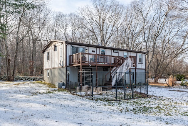 snow covered back of property featuring a deck