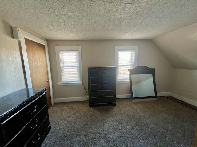 unfurnished bedroom featuring dark carpet and lofted ceiling