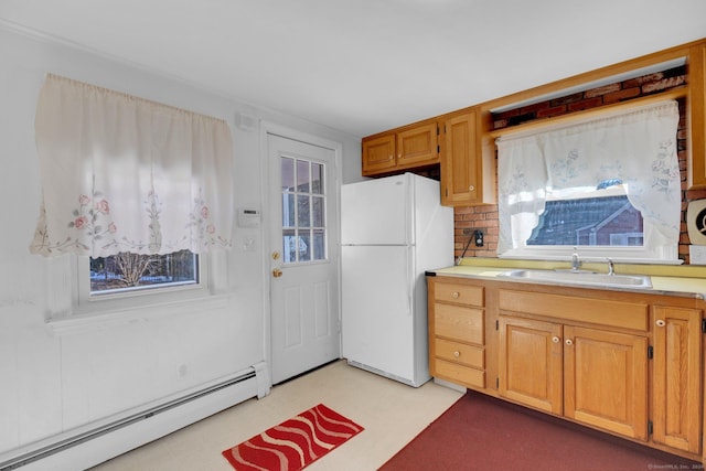 kitchen featuring white fridge, plenty of natural light, baseboard heating, and sink