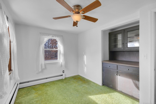 carpeted empty room featuring ceiling fan and a baseboard heating unit