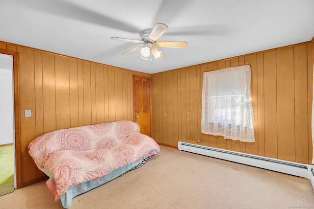 carpeted bedroom featuring a baseboard radiator, ceiling fan, and wood walls