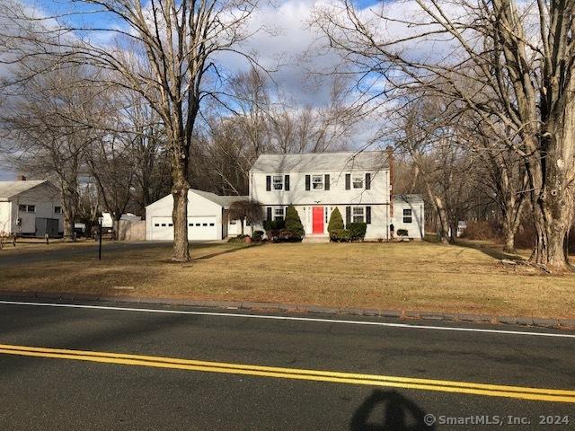 colonial home with an attached garage, a front yard, and a residential view