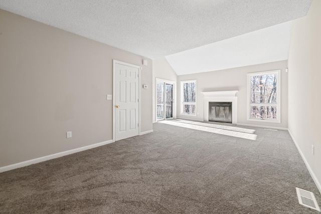 unfurnished living room with carpet flooring, vaulted ceiling, and a textured ceiling