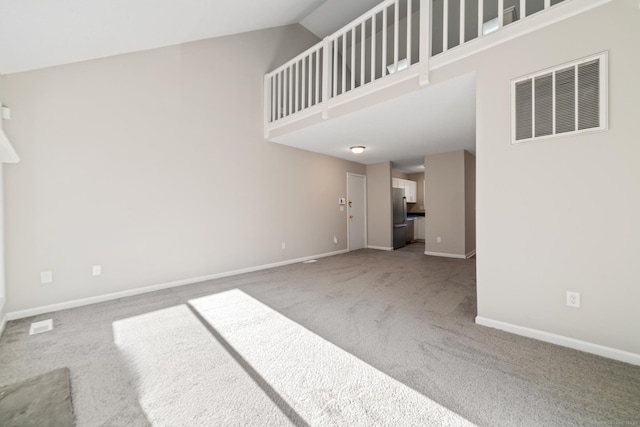 unfurnished living room with high vaulted ceiling and carpet flooring