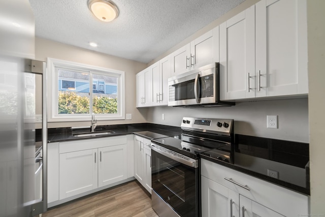 kitchen featuring white cabinetry, sink, light wood-type flooring, and appliances with stainless steel finishes