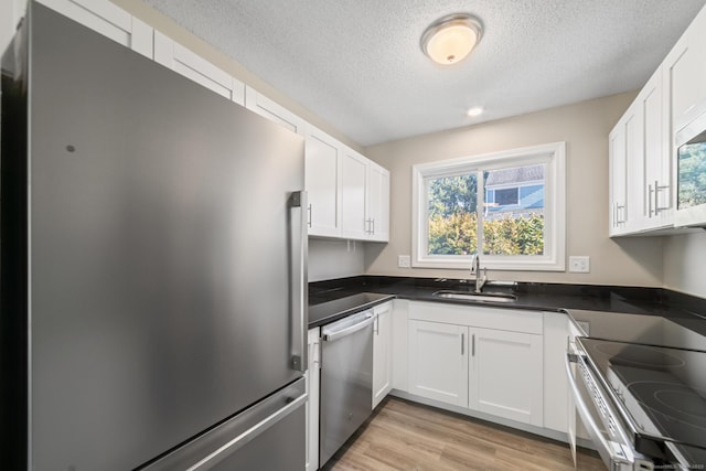 kitchen featuring white cabinetry, appliances with stainless steel finishes, sink, and light hardwood / wood-style flooring