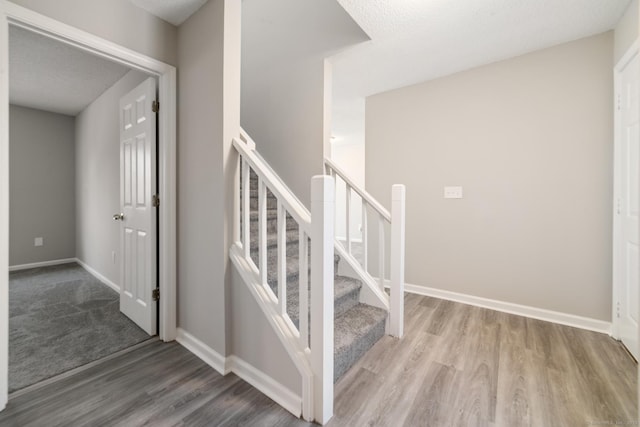 staircase with wood-type flooring and a textured ceiling