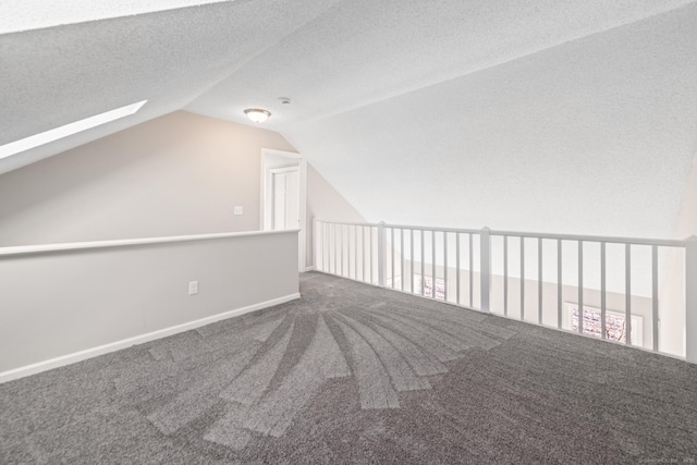 additional living space featuring vaulted ceiling with skylight, carpet floors, and a textured ceiling