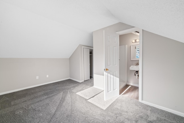 bonus room with lofted ceiling, sink, a textured ceiling, and carpet flooring