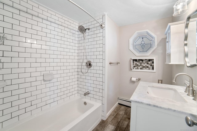 bathroom with hardwood / wood-style flooring, tiled shower / bath combo, vanity, and a baseboard heating unit