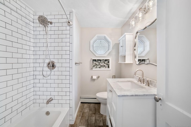 full bathroom featuring vanity, toilet, baseboard heating, and tiled shower / bath combo