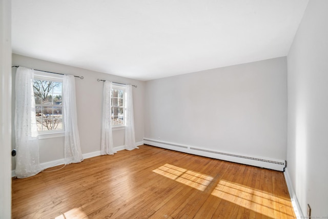 empty room with hardwood / wood-style flooring and a baseboard radiator