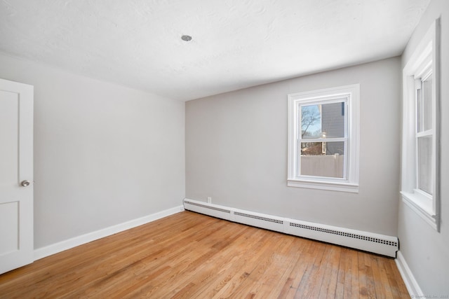 unfurnished room with light hardwood / wood-style flooring and a baseboard heating unit