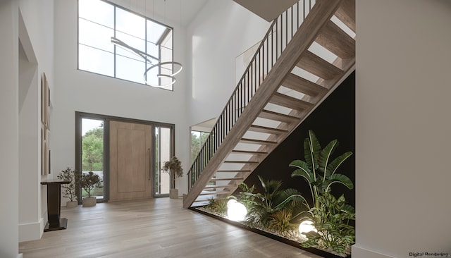 entryway featuring light wood-type flooring and a towering ceiling