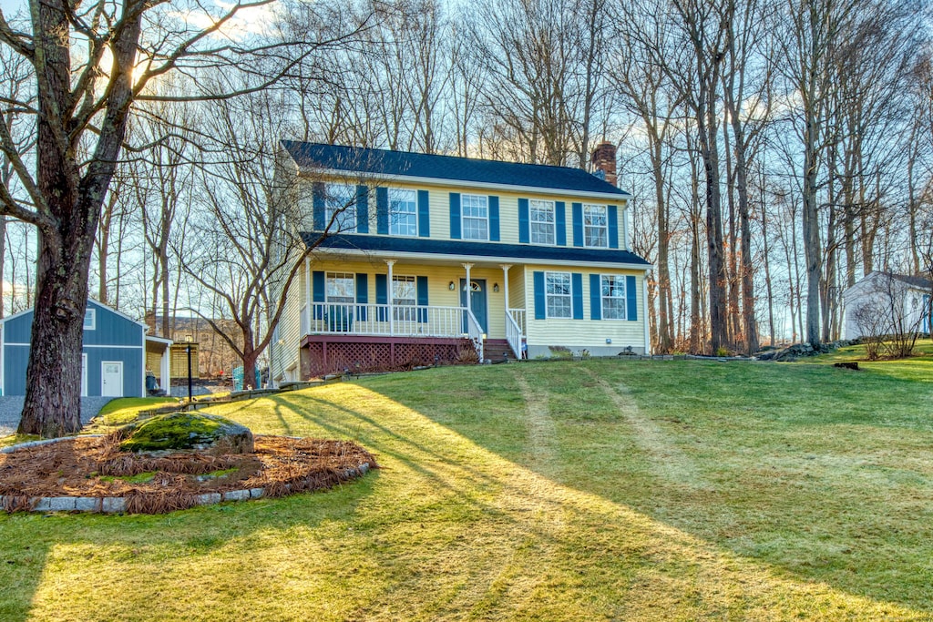 colonial home featuring covered porch and a front yard