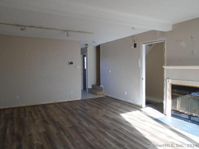 unfurnished living room with a fireplace, beamed ceiling, and hardwood / wood-style floors