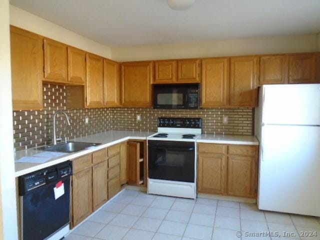 kitchen with tasteful backsplash, sink, light tile patterned floors, and black appliances