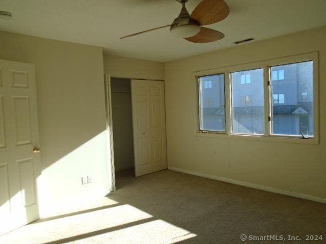 unfurnished bedroom featuring a closet, ceiling fan, and light colored carpet