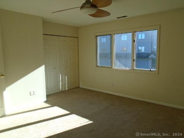 unfurnished bedroom with carpet flooring, a closet, and ceiling fan