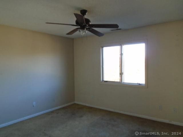 carpeted spare room with ceiling fan