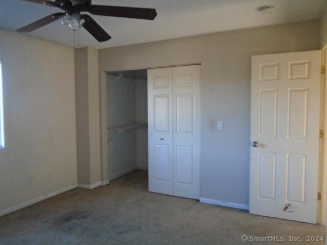 unfurnished bedroom featuring ceiling fan, a closet, and light carpet