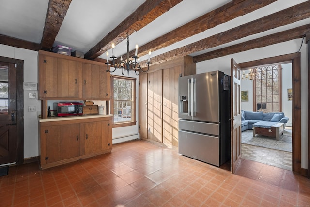 kitchen with brown cabinetry, baseboard heating, stainless steel fridge, and an inviting chandelier