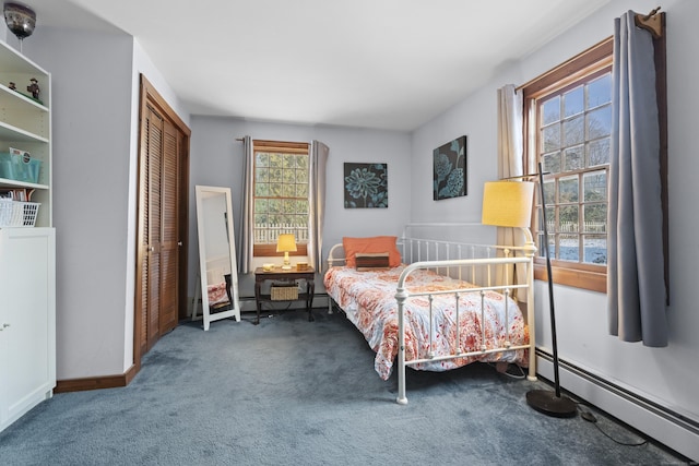 bedroom with a closet, baseboard heating, baseboards, and carpet