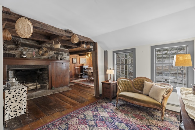 living room featuring wooden walls, a baseboard heating unit, vaulted ceiling, a stone fireplace, and dark wood-style floors