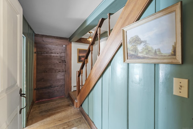 stairway with hardwood / wood-style flooring, a baseboard radiator, and wooden walls