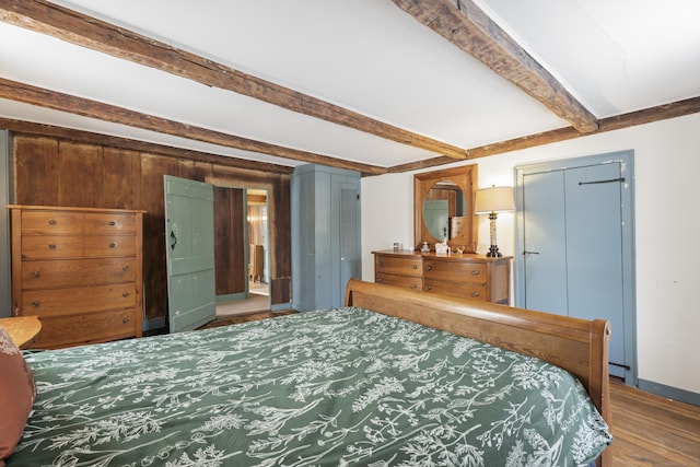 bedroom with hardwood / wood-style floors and beam ceiling