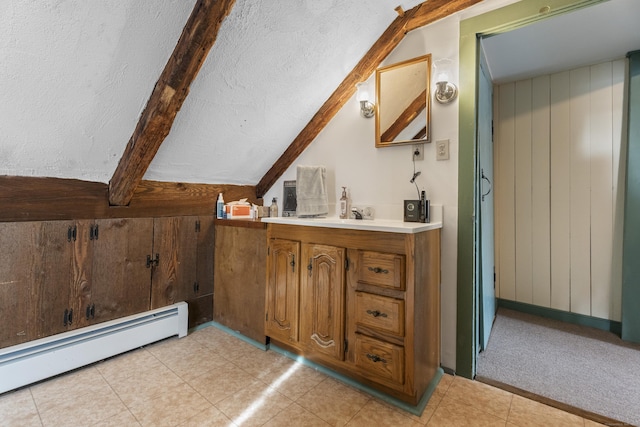 bathroom with a textured ceiling, wooden walls, baseboard heating, vaulted ceiling with beams, and vanity