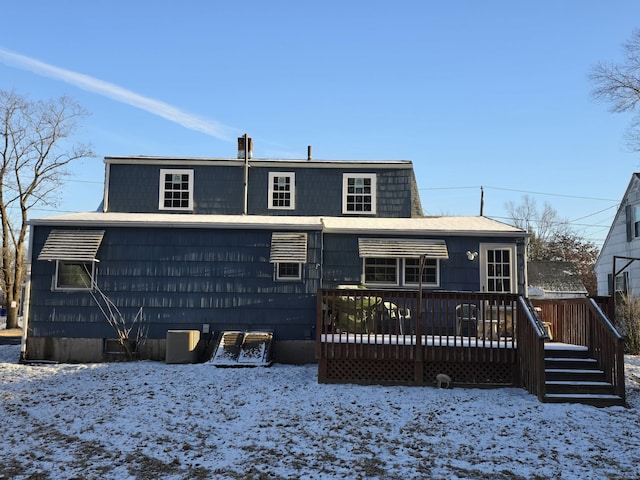 snow covered back of property with a wooden deck