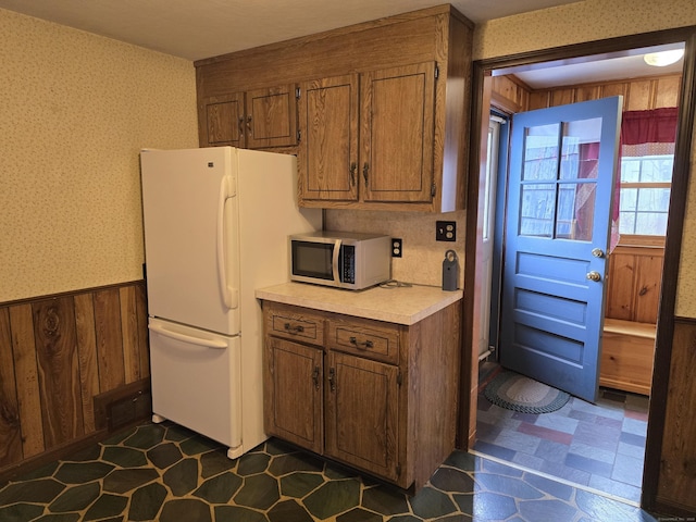 kitchen featuring white refrigerator and wood walls