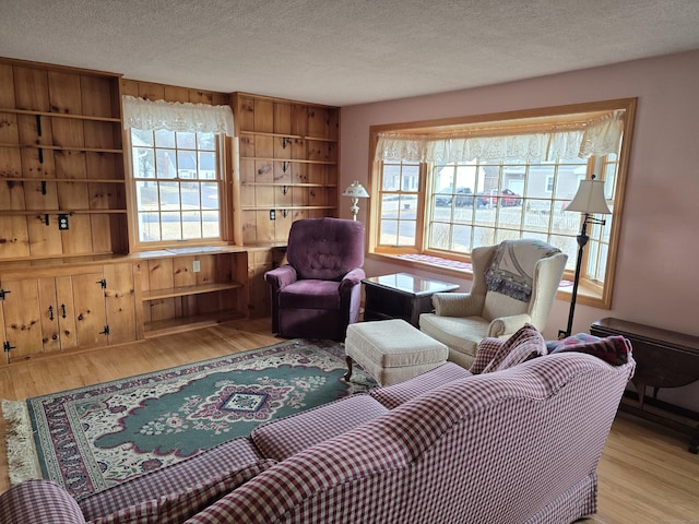 living room with built in features, a textured ceiling, and light hardwood / wood-style flooring