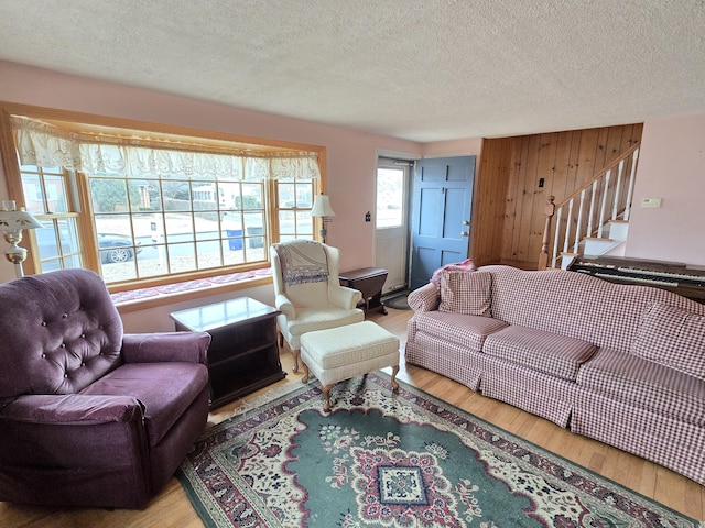 living room with wood-type flooring, a textured ceiling, plenty of natural light, and wood walls