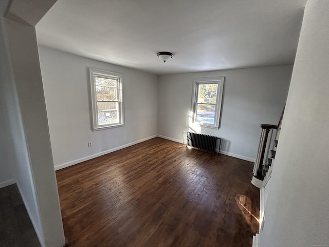 empty room featuring dark hardwood / wood-style flooring and radiator heating unit