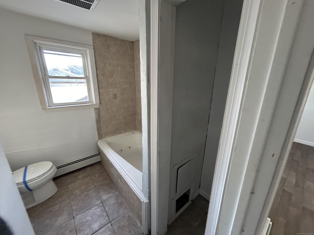 bathroom featuring a tub to relax in, toilet, and baseboard heating