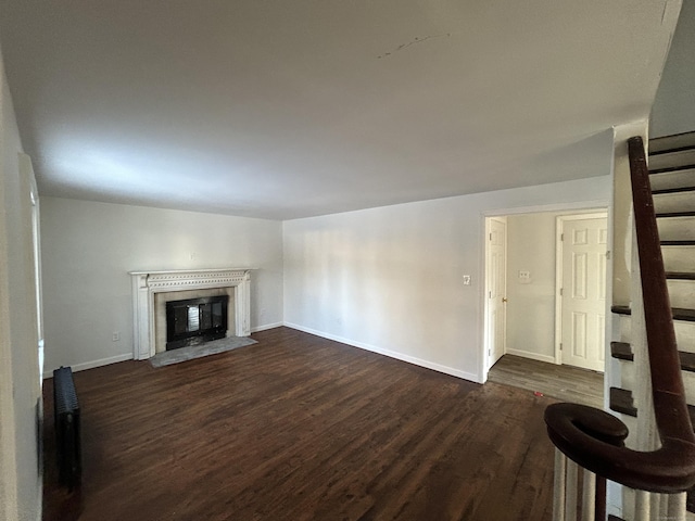 unfurnished living room featuring a premium fireplace and dark hardwood / wood-style flooring