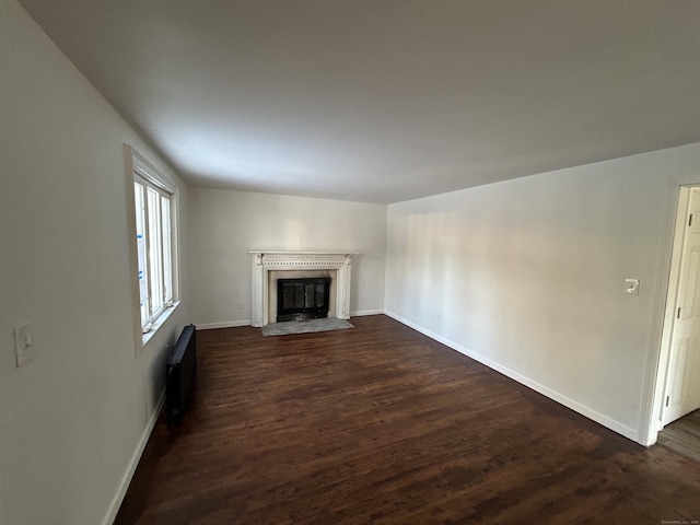 unfurnished living room with radiator heating unit and dark hardwood / wood-style flooring