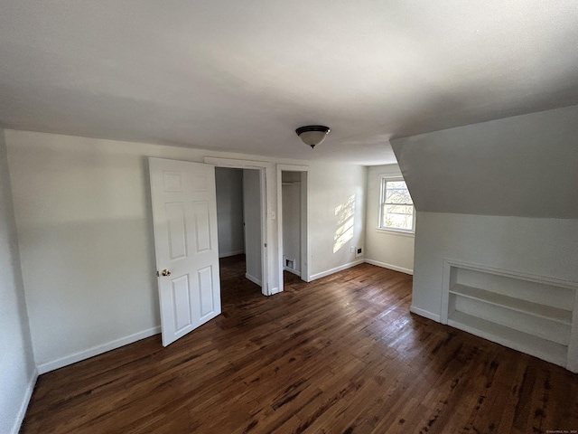 additional living space with dark hardwood / wood-style floors, built in features, and vaulted ceiling