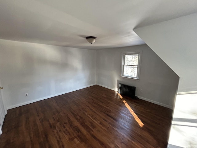 additional living space featuring radiator heating unit and dark hardwood / wood-style flooring