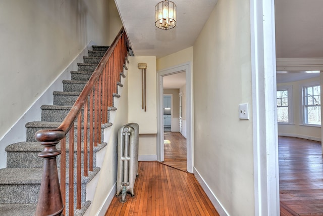 stairs with a chandelier, hardwood / wood-style flooring, and radiator