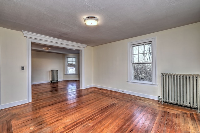 empty room featuring radiator, dark hardwood / wood-style flooring, and a textured ceiling